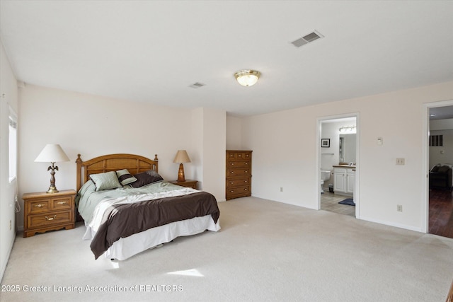 bedroom with light carpet, baseboards, visible vents, and connected bathroom