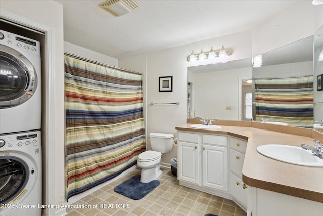 full bathroom featuring visible vents, double vanity, a sink, and stacked washer and clothes dryer