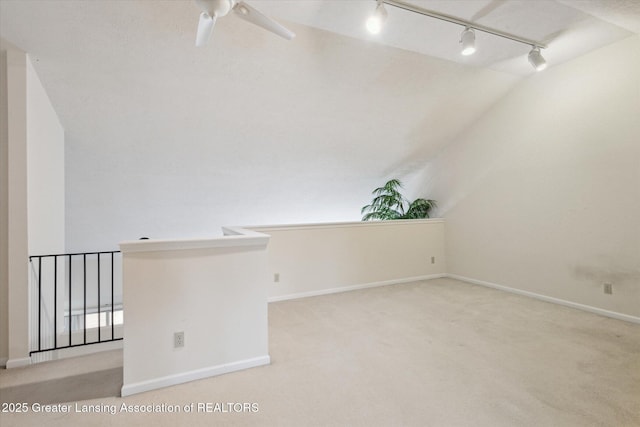 unfurnished room featuring a ceiling fan, light colored carpet, vaulted ceiling, and baseboards