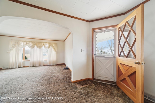 entrance foyer featuring arched walkways, dark carpet, baseboards, and crown molding