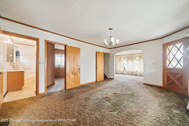 interior space featuring an inviting chandelier, carpet, ornamental molding, and arched walkways