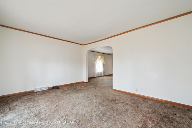 carpeted empty room with baseboards, arched walkways, and ornamental molding