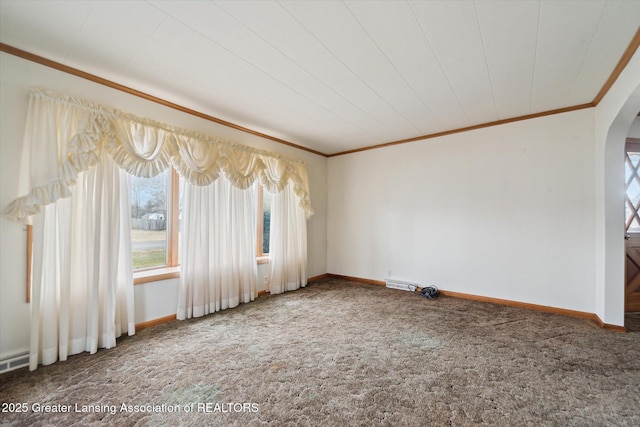 carpeted empty room with baseboards, arched walkways, and ornamental molding