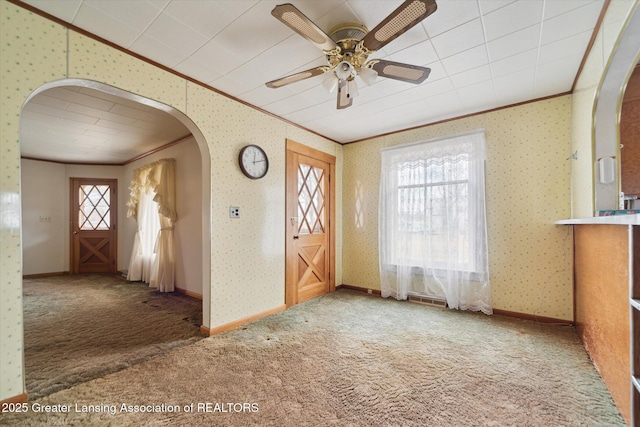 carpeted foyer with wallpapered walls, baseboards, arched walkways, ornamental molding, and vaulted ceiling