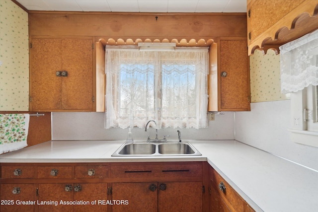 kitchen featuring brown cabinetry, light countertops, and a sink