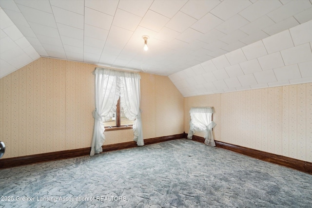 additional living space featuring carpet flooring, vaulted ceiling, baseboards, and wallpapered walls