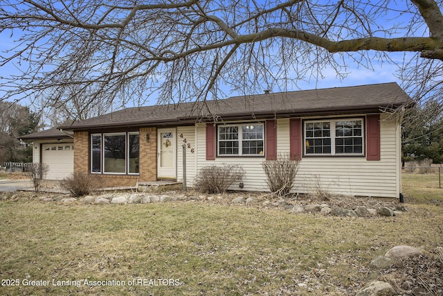 ranch-style home featuring an attached garage, fence, a front lawn, and brick siding