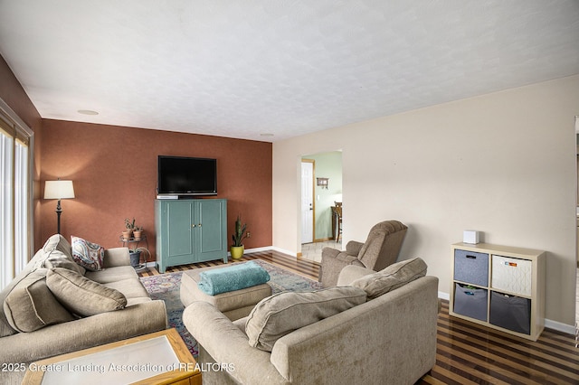 living area featuring a textured ceiling, dark wood-type flooring, and baseboards