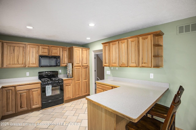 kitchen with visible vents, a peninsula, light countertops, black appliances, and a kitchen bar