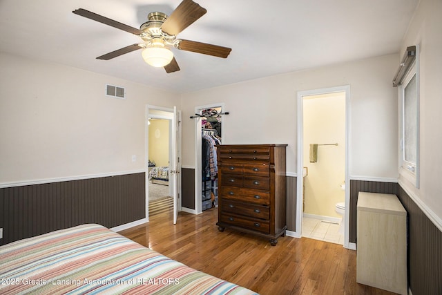 bedroom featuring visible vents, a ceiling fan, connected bathroom, wood finished floors, and baseboards