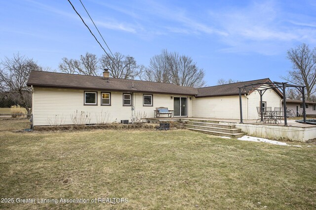 rear view of property featuring a deck, a yard, a chimney, and fence