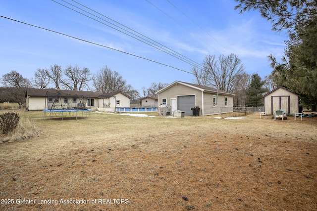 view of yard with a storage unit, a trampoline, fence, and an outdoor structure