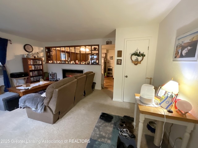 carpeted living room with a warm lit fireplace