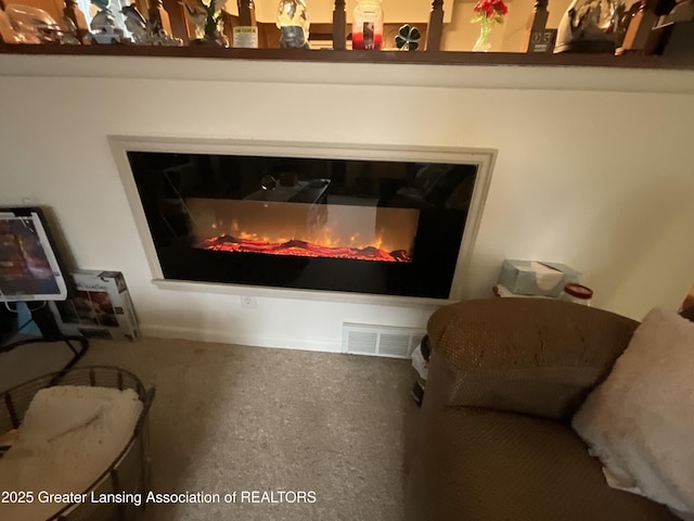 room details featuring a glass covered fireplace, visible vents, and heating unit