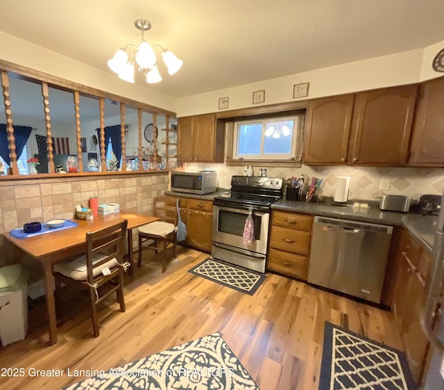 kitchen featuring dark countertops, light wood-type flooring, a chandelier, and stainless steel appliances