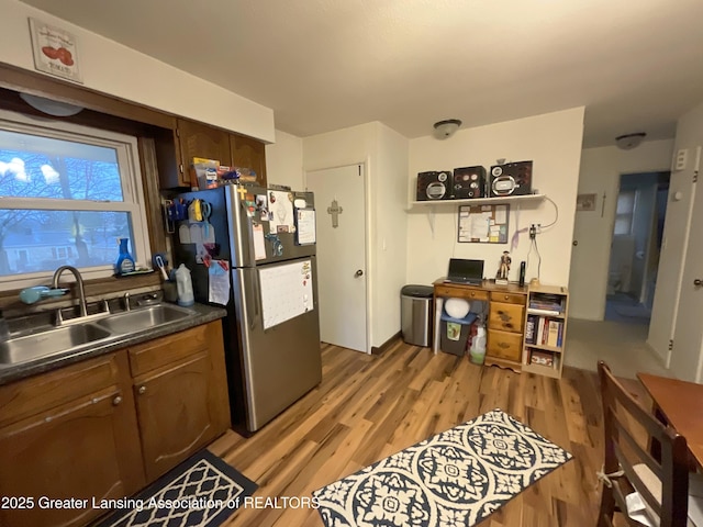 kitchen featuring dark countertops, light wood-style floors, a sink, and freestanding refrigerator