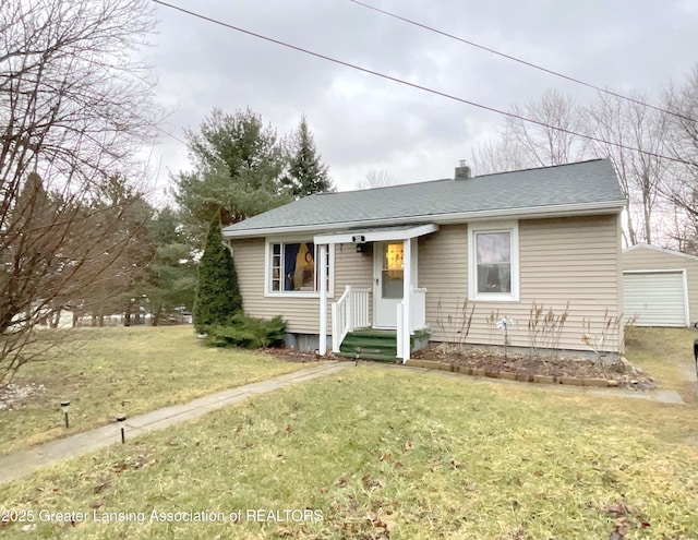 view of front of house with a garage, an outbuilding, a front lawn, and roof with shingles