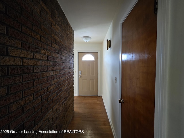 entryway with brick wall, baseboards, and dark wood finished floors