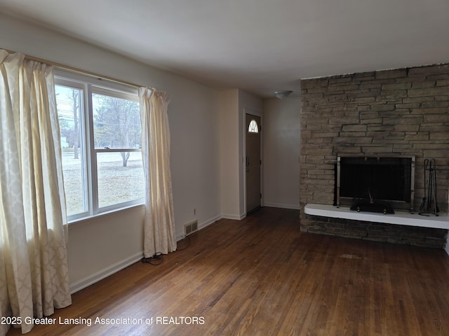 unfurnished living room featuring a fireplace, wood finished floors, visible vents, and baseboards