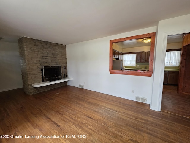 unfurnished living room featuring visible vents, a fireplace, and wood finished floors