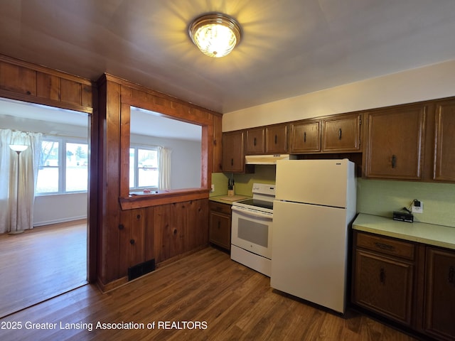 kitchen with white appliances, visible vents, dark wood-type flooring, light countertops, and under cabinet range hood