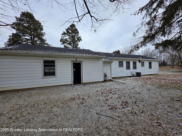 back of property featuring central AC unit and a chimney