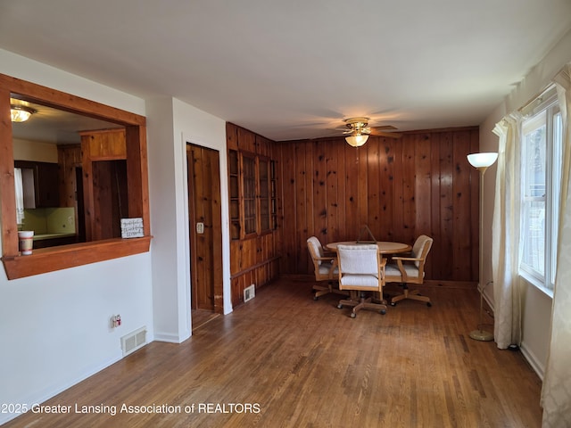 dining space with a ceiling fan, visible vents, baseboards, and wood finished floors