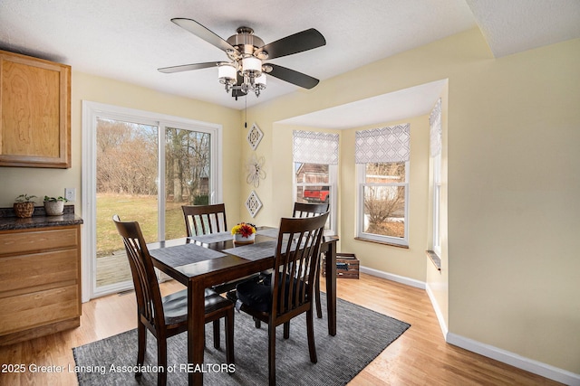 dining area featuring light wood finished floors, a ceiling fan, and baseboards