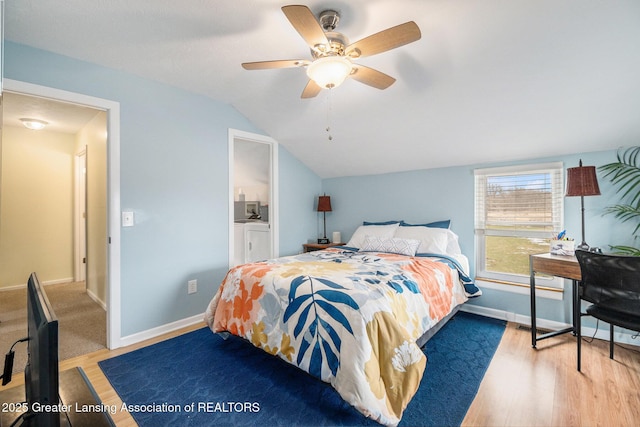 bedroom featuring vaulted ceiling, baseboards, wood finished floors, and washer and dryer