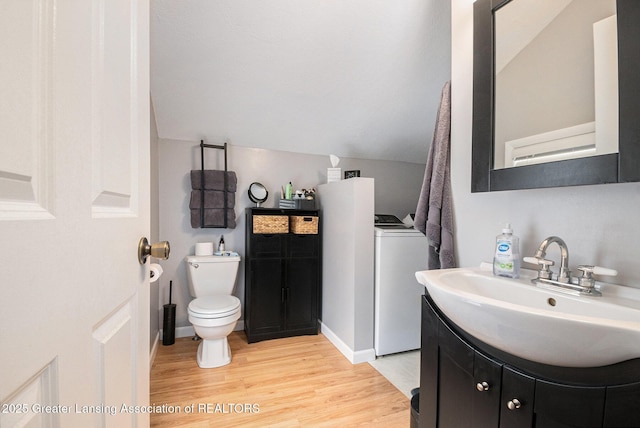 bathroom with lofted ceiling, toilet, wood finished floors, vanity, and washer / clothes dryer