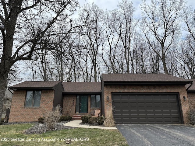 view of front of property featuring a shingled roof, brick siding, driveway, and an attached garage