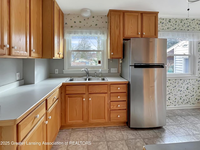 kitchen with a wealth of natural light, freestanding refrigerator, light countertops, and a sink