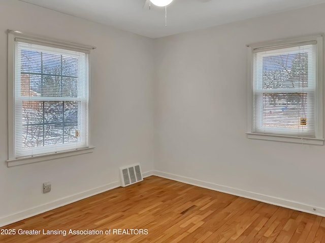 spare room with light wood-style flooring, visible vents, and baseboards