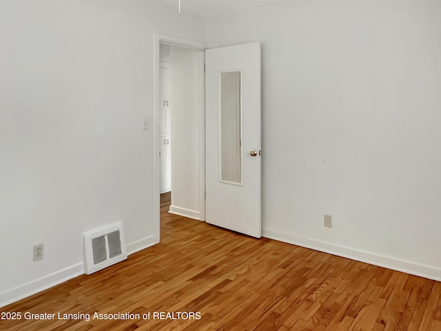 spare room with light wood-type flooring, baseboards, and visible vents