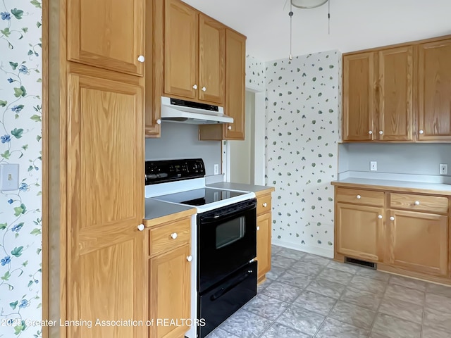 kitchen with under cabinet range hood, range with electric cooktop, visible vents, light floors, and wallpapered walls