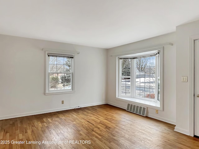 spare room with baseboards, visible vents, and hardwood / wood-style floors