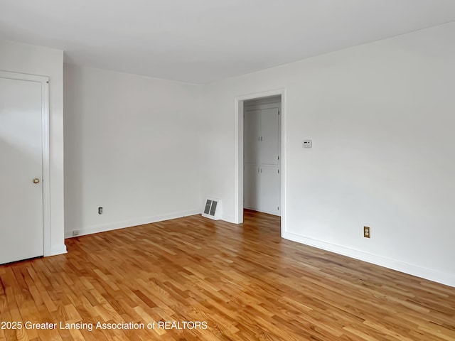 unfurnished room featuring light wood finished floors, baseboards, and visible vents