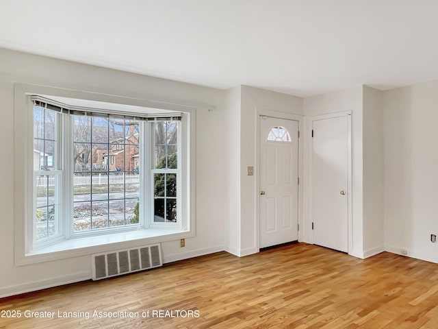 foyer entrance featuring baseboards, visible vents, and light wood-style floors