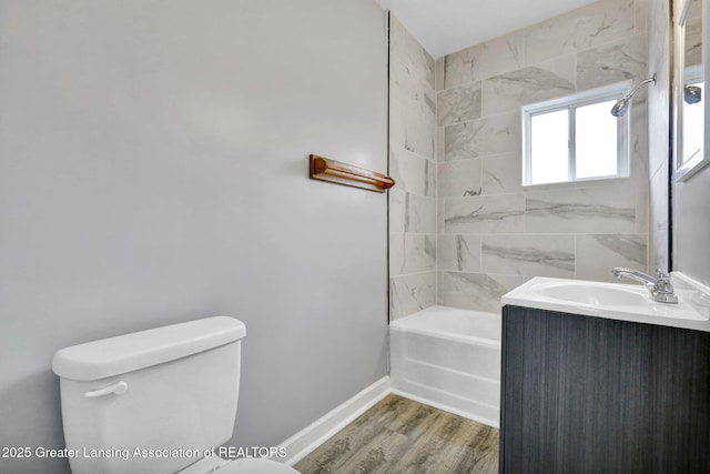 full bath featuring vanity, wood finished floors, baseboards,  shower combination, and toilet