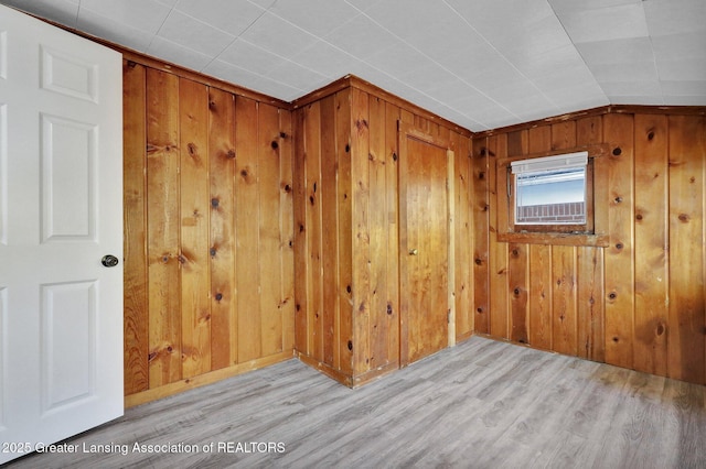 empty room with lofted ceiling, light wood-type flooring, and wood walls