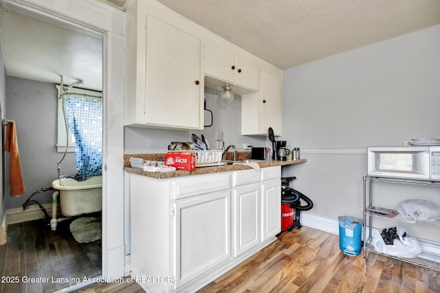 kitchen featuring white cabinets, light wood-style flooring, and a sink