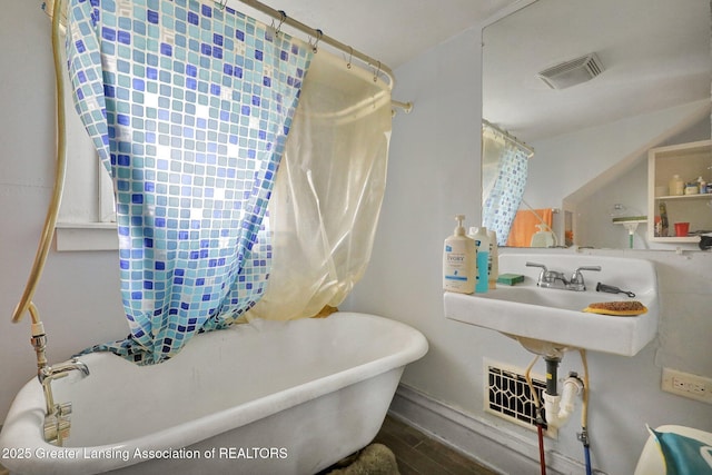 full bath featuring wood finished floors, a bathtub, and visible vents