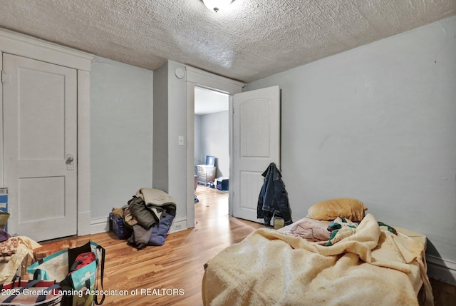 bedroom with a textured ceiling and wood finished floors