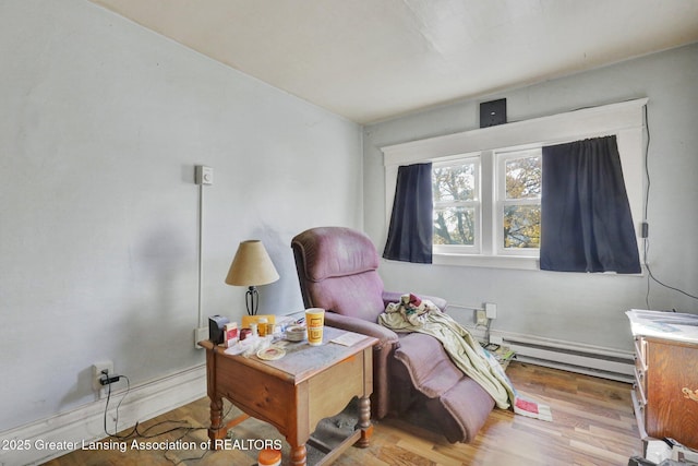 sitting room with baseboard heating and light wood-style flooring