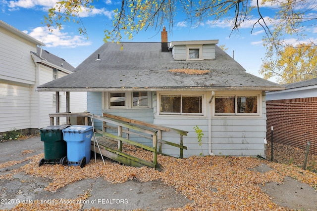 view of front of home featuring a chimney and a shingled roof