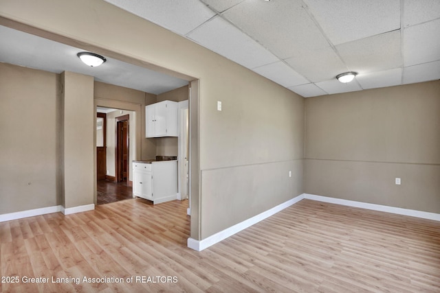 unfurnished room with light wood finished floors, baseboards, and a drop ceiling