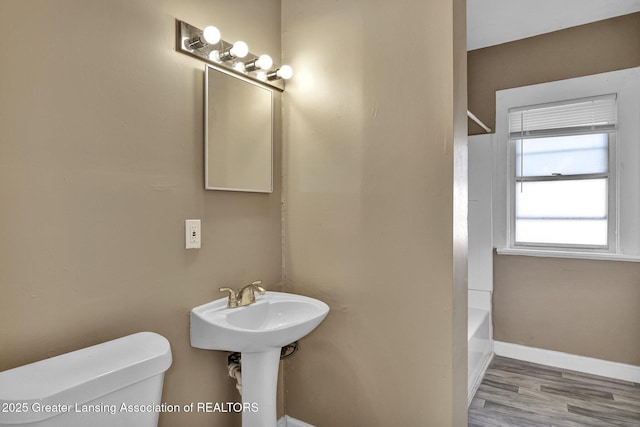 full bathroom featuring a tub to relax in, toilet, wood finished floors, baseboards, and a shower