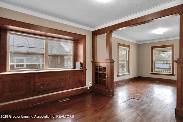 unfurnished room featuring dark wood-style floors, baseboards, visible vents, and ornamental molding