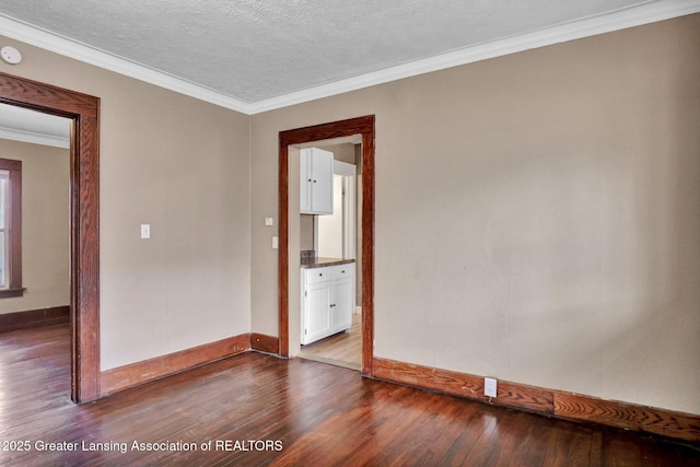 spare room with crown molding, a textured ceiling, baseboards, and dark wood-style flooring