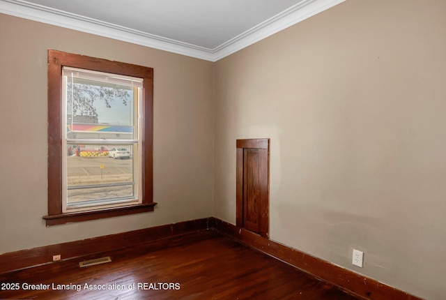 spare room featuring visible vents, baseboards, dark wood finished floors, and crown molding